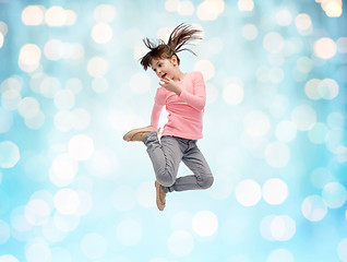 Image showing happy little girl jumping in air over blue lights