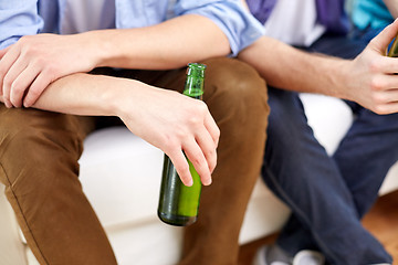 Image showing close up of male friends drinking beer at home