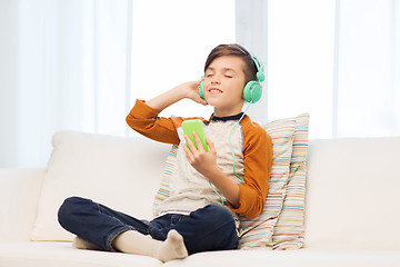 Image showing happy boy with smartphone and headphones at home