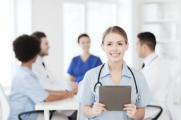 Image showing happy doctor with tablet pc over team at clinic