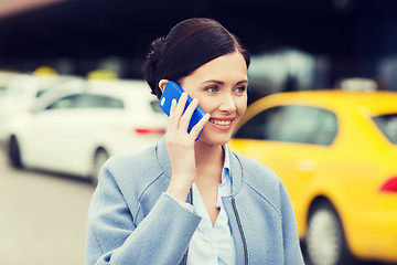 Image showing smiling woman with smartphone over taxi in city