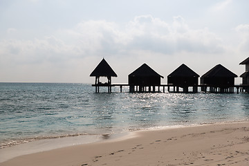 Image showing bungalow huts in sea water on exotic resort beach