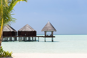 Image showing bungalow huts in sea water on exotic resort beach