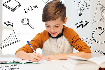 Image showing smiling student boy writing to notebook at home