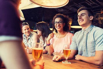 Image showing happy friends drinking beer and talking at bar