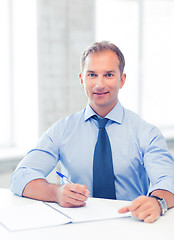 Image showing handsome businessman writing in notebook