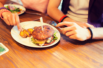 Image showing close up of friends hands sharing burger at bar