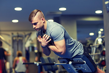 Image showing young man flexing back muscles on bench in gym