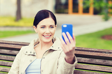 Image showing smiling woman taking picture with smartphone