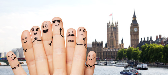 Image showing close up of fingers with smiley faces over london