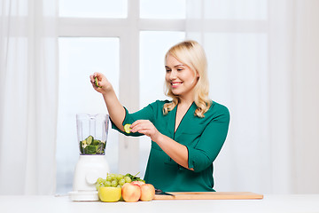 Image showing smiling woman with blender cooking food at home