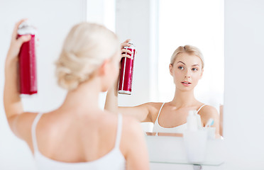 Image showing woman with hairspray styling her hair at bathroom