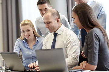Image showing smiling businesspeople with laptops in office
