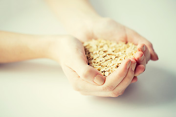 Image showing close up of woman hands holding oatmeal flakes