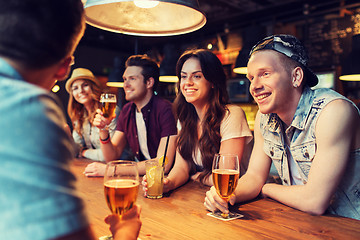 Image showing happy friends with drinks talking at bar or pub