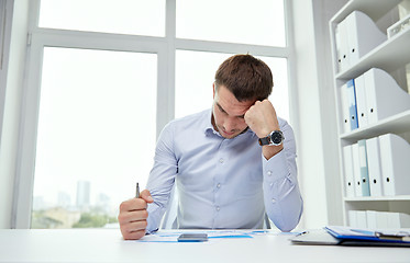 Image showing stressed businessman with papers in office