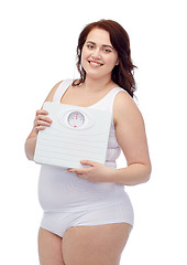 Image showing happy young plus size woman holding scales