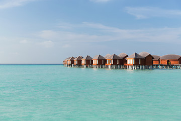 Image showing bungalow huts in sea water on exotic resort beach