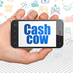 Image showing Business concept: Hand Holding Smartphone with Cash Cow on display