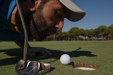 Image showing golf player blowing ball in hole