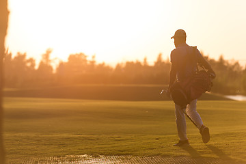 Image showing golfer  walking and carrying golf  bag at beautiful sunset