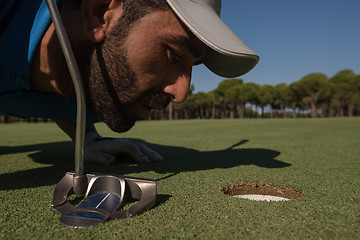 Image showing golf player blowing ball in hole