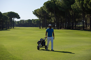 Image showing golf player walking with wheel bag