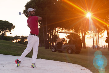 Image showing golfer hitting a sand bunker shot on sunset