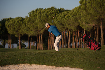 Image showing golfer hitting a sand bunker shot on sunset