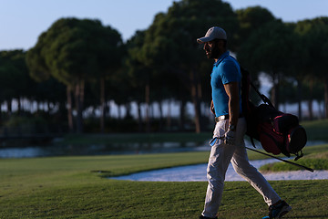 Image showing golfer  walking and carrying golf  bag at beautiful sunset