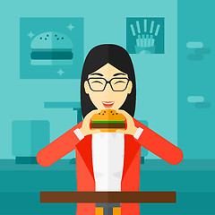 Image showing Woman eating hamburger. 