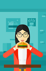 Image showing Woman eating hamburger. 