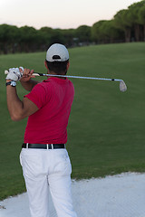 Image showing golfer hitting a sand bunker shot on sunset