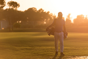 Image showing golfer  walking and carrying golf  bag at beautiful sunset