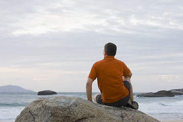 Image showing Man sitting on a rock at the sea