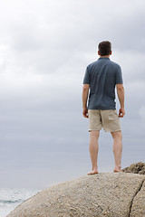 Image showing Man standing on a rock at the sea