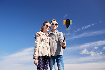 Image showing happy girls with smartphone selfie stick