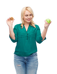 Image showing smiling woman choosing between apple and cookie