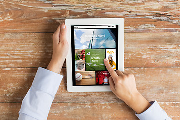 Image showing close up of hands with news app on tablet pc