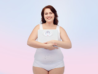 Image showing happy young plus size woman holding scales