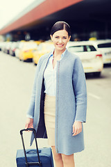 Image showing smiling young woman with travel bag over taxi