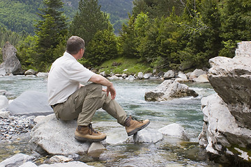 Image showing Hiker sitting at a mountain creek