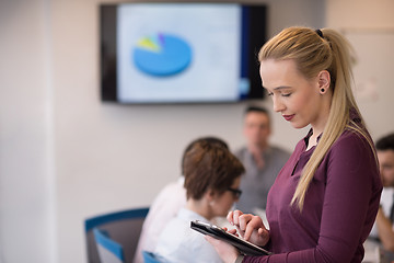 Image showing blonde businesswoman working on tablet at office