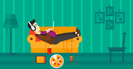 Image showing Man lying on sofa with many gadgets.