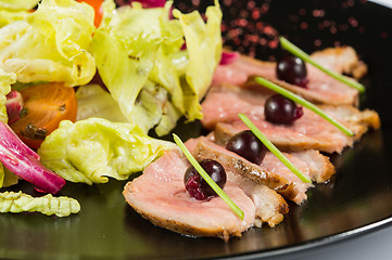 Image showing grilled meat with lettuce. on black plate