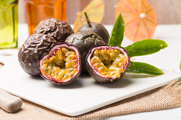 Image showing Passion fruits on white ceramic tray on wooden table background.