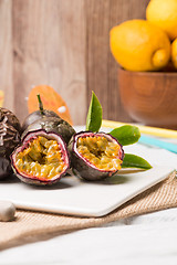 Image showing Passion fruits on white ceramic tray on wooden table background.