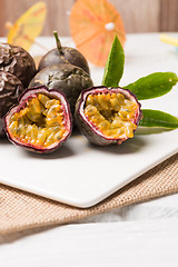 Image showing Passion fruits on white ceramic tray on wooden table background.