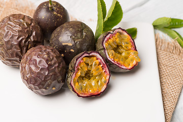 Image showing Passion fruits on white ceramic tray on wooden table background.