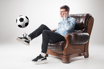 Image showing The portrait of fan with ball, holding  tv remote on white background